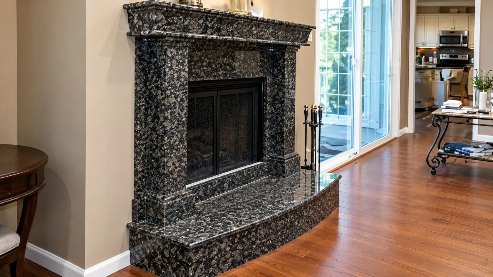 Living room fireplace with a dark speckled stone surround and hearth on a wood floor